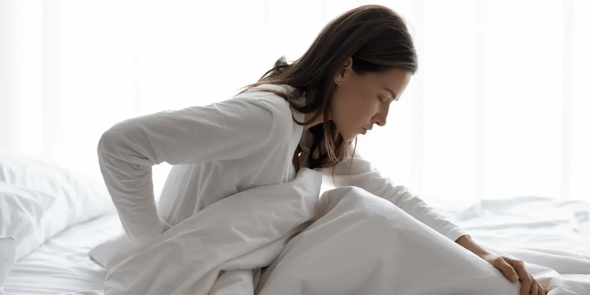 mulher na cama sofrendo com dor devido a hérnia de disco